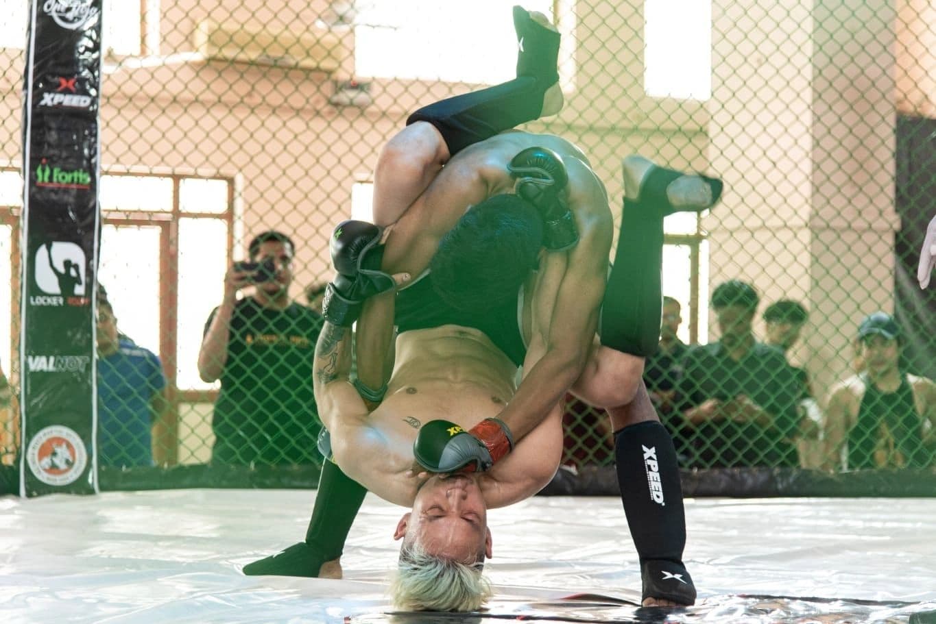 A fighter lifts his opponent upside down for a slam inside the cage, Devils Octagon Season One
