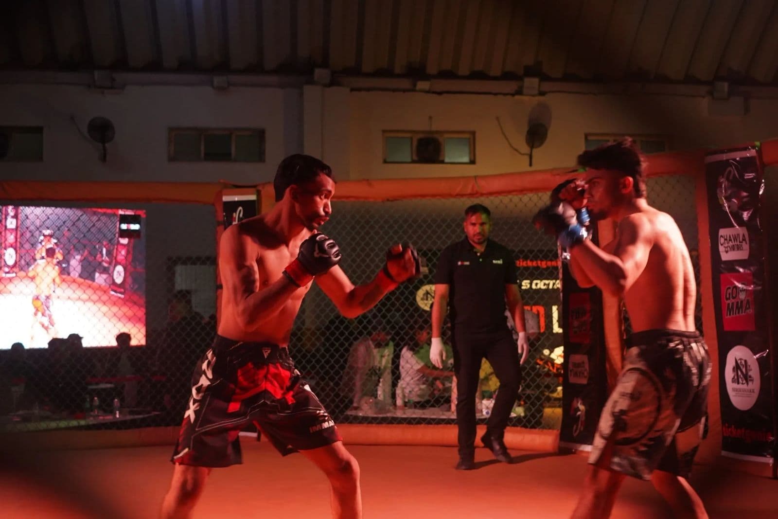 Two fighters square off as the referee watches, at The Red League's debut night